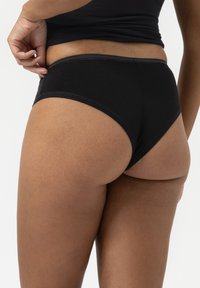 Zwarte katoenen slip met een middellange snit en soepele randen. De stof lijkt zacht met een lichte glans, wat zorgt voor een gestroomlijnde silhouette.