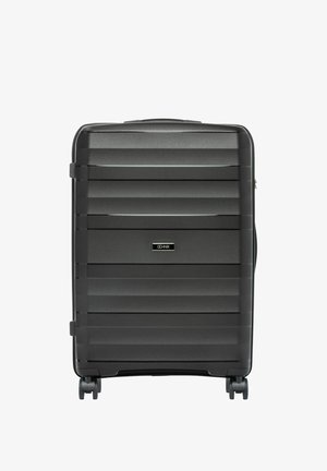 Czarna walizka z twardą skorupą z poziomymi żłobieniami, czterema obrotowymi kółkami oraz centralną etykietą marki na przednim panelu.