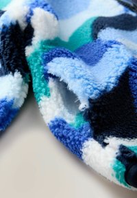 Fleece audums zilganzs, zaļganzs un melns ar abstraktu rakstu. Redzama mīksta tekstūra un izliekti maliņas.