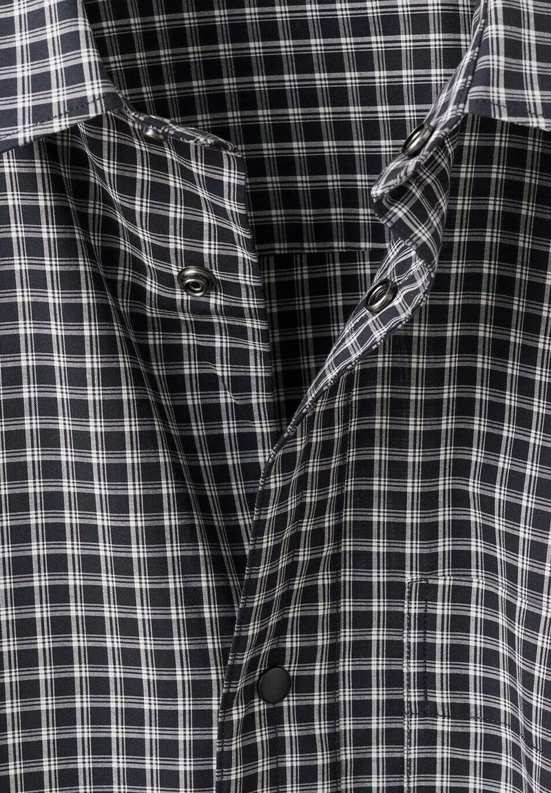 Black and white checkered shirt with a soft cotton fabric, featuring a pointed collar, front buttons, and a chest pocket.