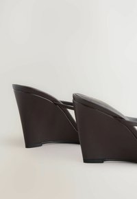 Sandales à talons compensés marron foncé avec un talon arrondi et des fines lanières, présentées de côté sur un fond clair.