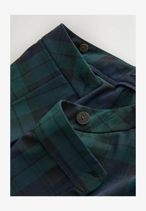 Tessuto a quadri verde e blu navy con una texture liscia, featuring due chiusure a bottone e dettagli del colletto piegato.