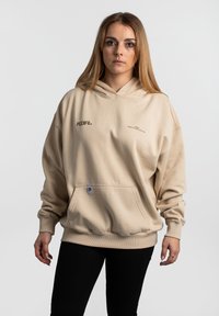 Beige übergroßer Hoodie aus weichem Stoff, mit einer Kängurutasche vorne, Logo-Print auf der Brust und gerippten Bündchen und Saum.