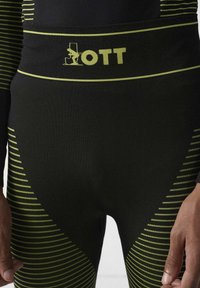 Zwarte compressiebroek met limegroene strepen en logo. Voorzien van een strakke pasvorm en een elastische tailleband voor comfortabel dragen.