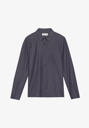 Camisa de botones gris oscuro con cuello puntiagudo, mangas largas y botones negros, que presenta una tela texturada y un corte holgado.