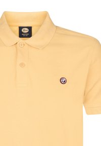 Polo T-shirt in lichtgele katoen stof, met een klassieke kraag, een placket met drie knopen en een klein logopatch op de linkerkant van de borst.