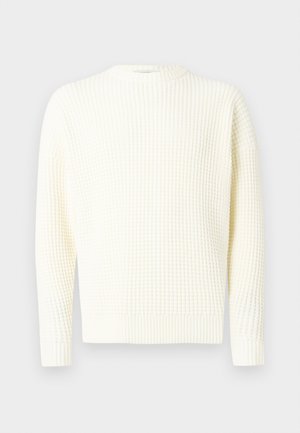 Camisola de malha waffle em branco off-white com decote redondo, punhos e bainha canelados. Textura suave, ajuste descontraído, mangas compridas.