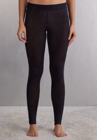 Svarta leggings gjorda av ett mjukt, töjbart material med hög midja. Tyget verkar något genomskinligt och har en slät yta.