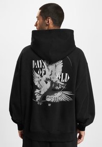 Czarna, oversize bluza z kapturem z graficznym wzorem przedstawiającym dwa ptaki oraz napisem "DAYS OF OLD" na plecach. Wykonana z miękkiego materiału, posiada dużą kieszeń i kaptur.