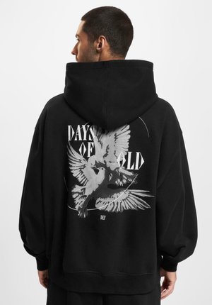 Svart oversized hettegenser med grafisk design av to fugler og teksten "DAYS OF OLD" på baksiden. Laget av myk stoff, med en stor hette.
