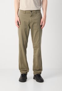 Khaki chinos made of cotton, featuring a straight leg design, front pockets, and a button closure. Worn with black sneakers.