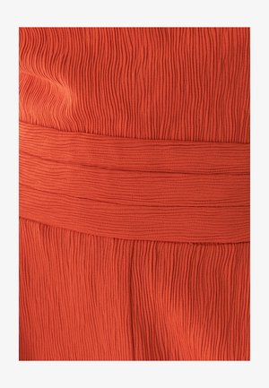 Rebrasta oranžna tkanina z gladkim elastičnim pasom. Tekstura vsebuje ponavljajoče se navpične črte, ki dodajajo dimenzijo in zanimivost.