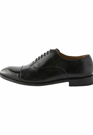Zapato de vestir negro de cuero con puntera redonda, textura suave, diseño de cordones y detalles de costura sutiles a lo largo de la parte superior. Suela plana.
