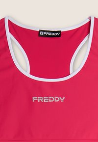 Bra sportivo FREDDY in tessuto rosa brillante con dettagli bianchi. Caratterizzato da scollatura a barca, dorso scoperto e logo metallico sul davanti.