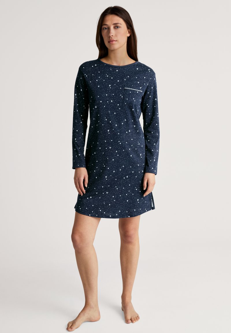 Camicia da notte blu navy a maniche lunghe con un motivo stellato, scollo rotondo solido e una piccola tasca sul petto. Le fessure laterali aumentano il comfort.