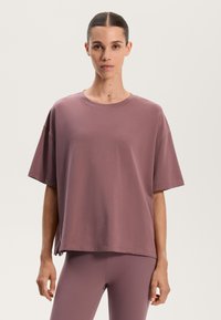 Løs siddende kortærmet t-shirt i en støvet rosesfarve, lavet af blødt stof med en rund halsudskæring og sidesplitter ved kanten.