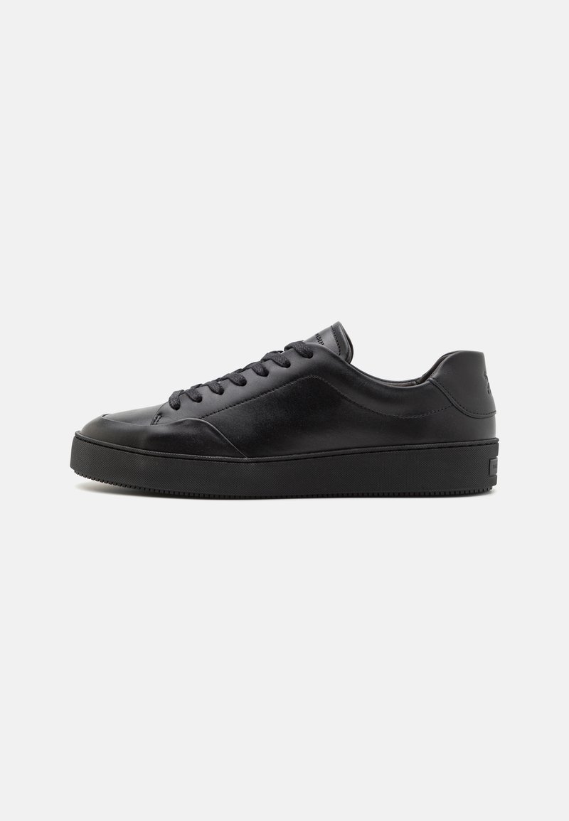 Black leather sneakers with a rounded toe, flat laces, and a textured rubber sole. Features a subtle logo on the heel and smooth finish.