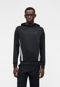 Sweatshirt preta com capuz e riscas brancas nas laterais, feita de tecido liso, com um pequeno logótipo no peito. Corte justo com punhos canelados.