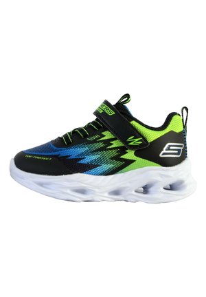 Zapatilla deportiva negra y verde neón con parte superior sintética, diseño de malla transpirable, patrón en zigzag y suela acolchada blanca. Incluye una correa de Velcro.