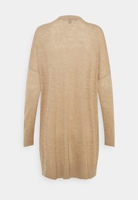 Lungo maglione beige con una vestibilità rilassata, caratterizzato da un colletto tondo, maniche lunghe e polsini a costine. Realizzato in un materiale morbido e strutturato.