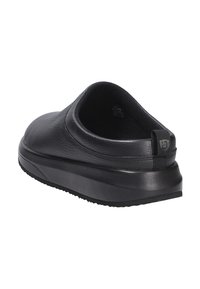 Scarpa nera senza lacci con tomaia in pelle testurizzata, design arrotondato, suola imbottita e un piccolo tirante sul tallone per una facile calzata.