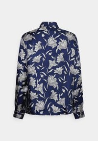 Blusa blu navy con motivo floreale bianco, maniche lunghe, design con colletto e texture liscia. La vista posteriore mostra una copertura floreale completa.