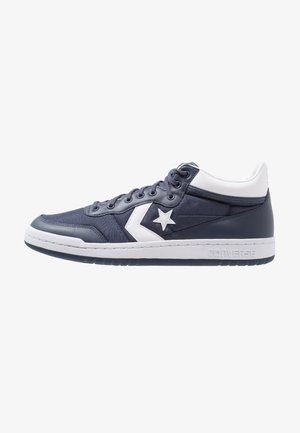 Dark navy sneakers with white accents, featuring a star logo, textured fabric, round toe, and a white rubber sole.