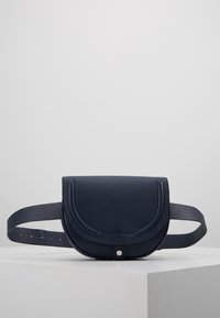 Granatowa skórzana nerka z zaokrągloną klapką, regulowanym paskiem i subtelnym wytłoczonym logo. Teksturowana powierzchnia o czystych liniach.