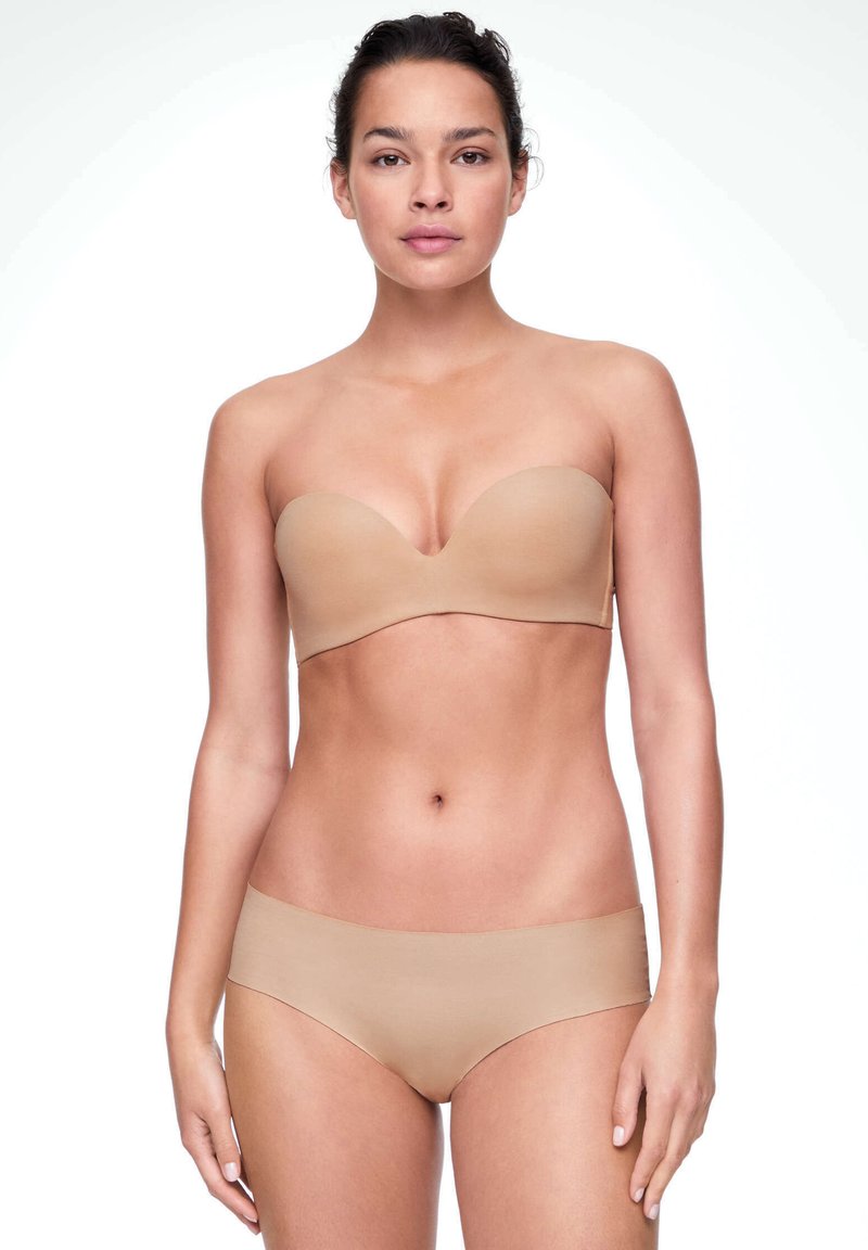 Soutien-gorge beige sans bretelles et culottes sans coutures, fabriqués en tissu lisse, avec un design minimaliste et une teinte de peau naturelle.