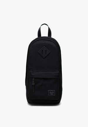 Zaino nero Herschel con tasca frontale con zip, manico superiore e patch in pelle a forma di diamante sul pannello frontale.