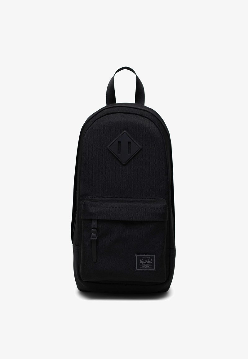 Sac à dos Herschel noir avec poche zippée à l'avant, poignée supérieure et écusson en cuir de forme diamant sur le panneau avant.