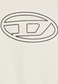 Pullover di colore crema con un prominente logo ovale nero caratterizzato da un design geometrico. Tessuto liscio con una leggera lucentezza.