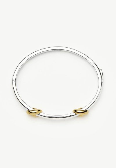 Ασημένιο βραχιόλι με δύο μικρά χρυσά δαχτυλίδια τοποθετημένα ομοιόμορφα γύρω από τη λωρίδα σε λευκό φόντο.