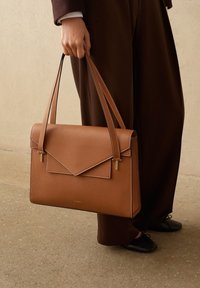Borsa a mano in pelle marrone con finitura testurizzata, forma rettangolare e patta stile busta. Presenta hardware in tonalità oro e due manici.