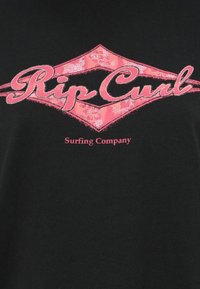 Must musta, kus on roosa "Rip Curl" logo lillemustriga, ja väike roosa tekst allpool, mis ütleb "Surfing Company."