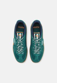 Adidași teal și portocalii cu un superior din suede și plasă, având detalii cu dungi, șireturi texturate și o talpă din cauciuc maro.