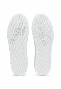 Białe gumowe podeszwy butów z wzorem chevron. "TOMMY JEANS" jest wytłoczone na każdej podeszwie, co dodaje dodatkowych detali i identyfikacji marki.