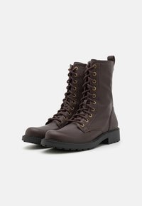 Bruine veterschoenen voor de strijd, gemaakt van soepel leer, met gouden ogen, een stevige zwarte rubberen zool en een trekhaak op de hiel.