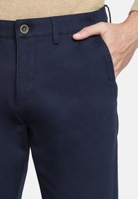 Chinos azul marino con una textura suave, que presentan un bolsillo frontal, un cierre de botón y costuras bien acabadas a lo largo de las costuras.