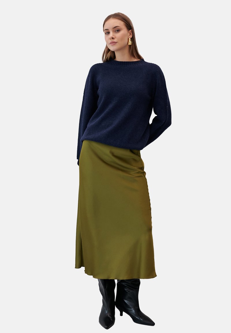 Granatowy sweter, wełniany, luźny krój. Oliwkowo-zielona satynowa spódnica, długości do kostek, z bocznym rozcięciem. Czarne skórzane buty za kolano.