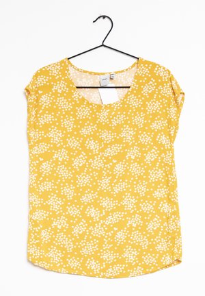 Top floreale giallo con scollatura a barca, maniche corte e vestibilità ampia. Presenta un piccolo motivo di fiori bianchi su tessuto morbido.