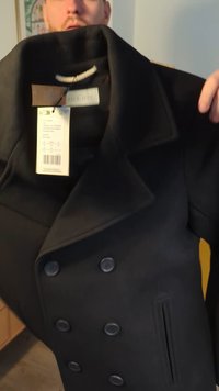 Cappotto doppiopetto nero in misto lana. Caratterizzato da grandi bottoni, ampio colletto e tasca laterale. Etichetta attaccata con informazioni sul prodotto.