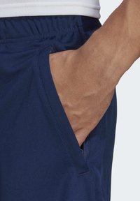 Námornícky modré športové šortky s elastickým pásom a bočnou vreckom, s hladkou textúrou a minimálnymi švovými detailami.