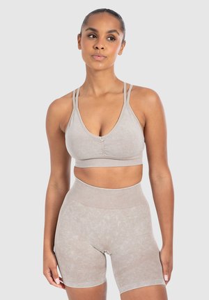Helle beige Sport-BH mit schmalen Trägern und Rundhalsausschnitt, kombiniert mit hoch geschnittenen Shorts mit strukturiertem Finish und geripptem Bund.
