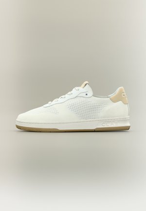 Weißer Sneaker mit niedrigem Schaft aus strukturiertem Stoff, Schnürverschluss, beiger Fersenlasche und beiger Außensohle, vor einem schlichten neutralen Hintergrund.