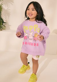 Vijoličasta jopa z motivom "Peppa in prijatelji" v rumeni in roza barvi, kombinirana z vzorčastimi kratkimi hlačami in svetlo rumenimi supergami.