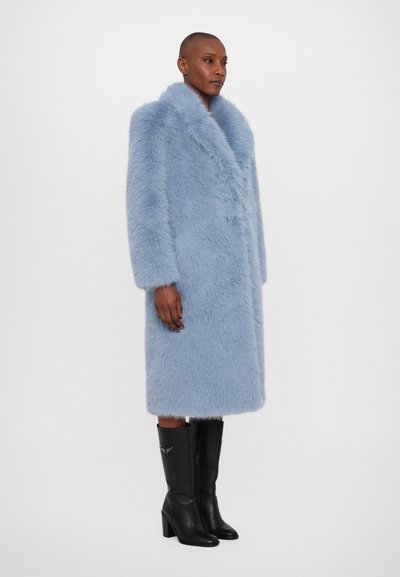 Abrigo de piel sintética azul claro con un cuello ancho, mangas largas y un diseño hasta la rodilla. Llevado con botas de tacón negras con detalles plateados.