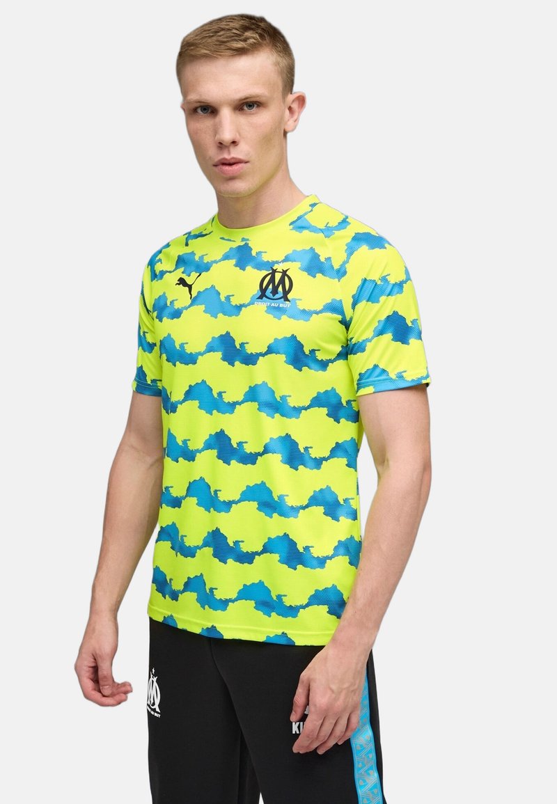 Short-sleeve sports shirt in bright neon yellow with blue, wavy camouflage pattern. Features black logo and textured fabric design.