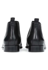 Botas Chelsea de cuero negro con paneles elásticos laterales, punta redonda y tacón bajo en bloque. Presentan una textura suave y dobles tiradores.