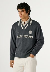 Siv sweater z bele pruge, s V-izrezom in logotipom "PEPE JEANS". Obut čez karirano srajco. Mehak na otip, z ribastimi manšetami.